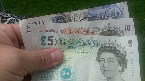 Three bank notes (UK money - £5, £10, £20) in hand 